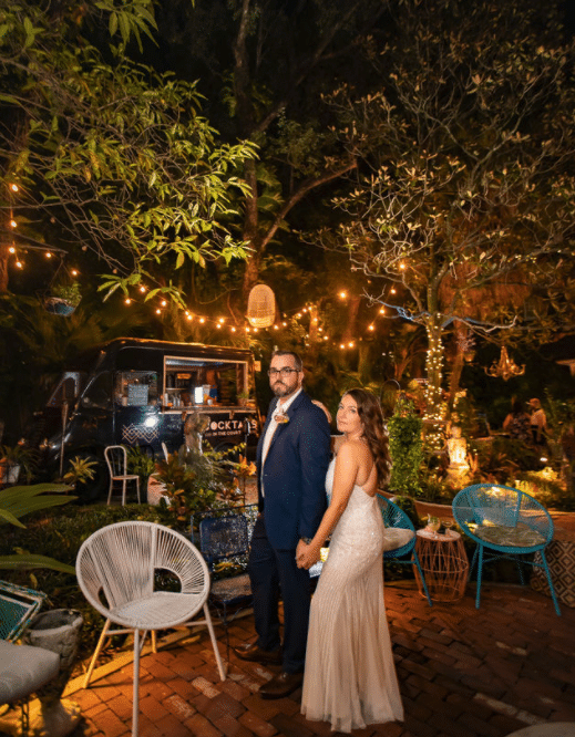 bride and groom on patio at night with string lights and white chairs